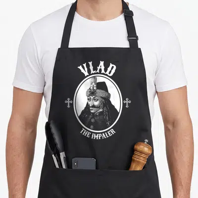 Tablier de cuisine noir avec portrait blanc de Vlad l'Empaleur encadré d'un ovale et des croix.