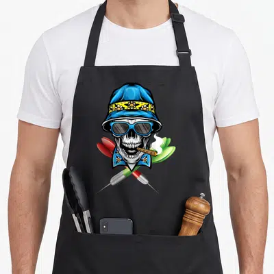Tablier de cuisine noir avec illustration d'un crâne portant un chapeau bleu et des lunettes de soleil au-dessus de deux fléchettes croisées.