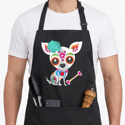 Tablier de cuisine noir avec illustration d'un chihuahua tête de mort en sucre aux couleurs vives et motifs floraux.