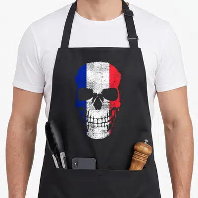 Tablier de cuisine noir avec un crâne aux couleurs du drapeau français et des détails football en style vintage.