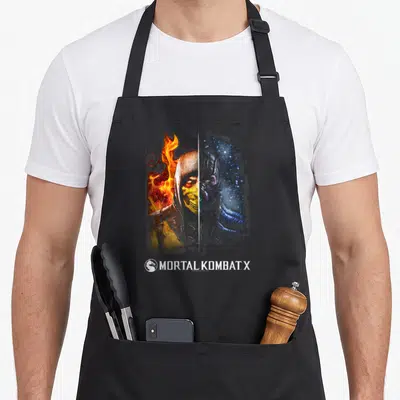 Tablier de cuisine noir avec illustration divisée de deux personnages aux éléments opposés et le logo Mortal Kombat X en bas.