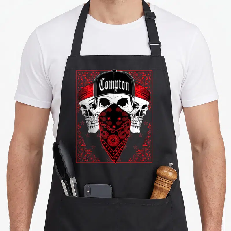 Tablier de cuisine noir avec trois têtes de mort portant une casquette Compton et un bandana rouge à motifs.