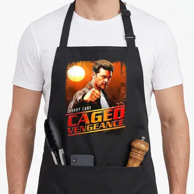 Tablier de cuisine noir avec Johnny Cage poing levé et texte Caged Vengeance en lettres rouges et oranges.