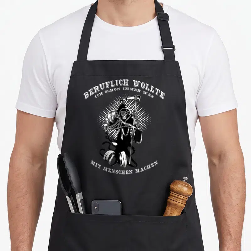 Tablier de cuisine noir avec illustration blanche de la Faucheuse et texte en allemand.