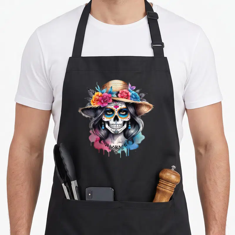 Tablier de cuisine noir avec une illustration de crâne femelle coiffé de roses et d'un chapeau de paille.