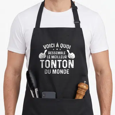 Tablier de cuisine noir avec inscription Voici à quoi ressemble le meilleur tonton du monde et deux pouces levés blancs.