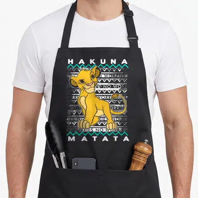 Tablier de cuisine noir avec Simba assis, texte Hakuna Matata et motifs tribaux gris et turquoise.