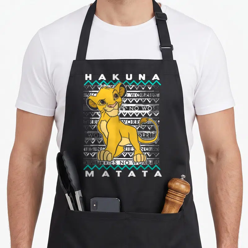 Tablier de cuisine noir avec Simba assis, texte Hakuna Matata et motifs tribaux gris et turquoise.