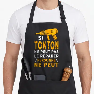 Tablier de cuisine noir avec une perceuse orange et le texte Si Tonton ne peut pas le réparer personne ne peut.
