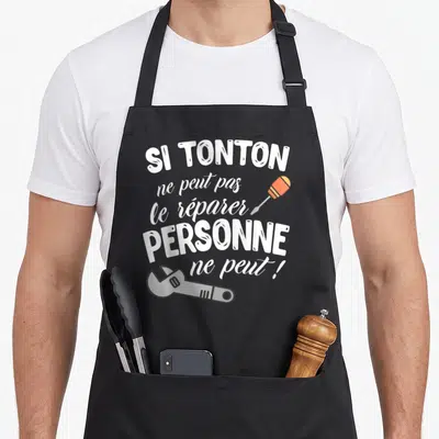 Tablier de cuisine noir avec inscription blanche et illustrations d'un tournevis et d'une clé à molette.