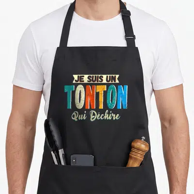 Tablier de cuisine noir avec l'inscription colorée Je Suis Un Tonton Qui Déchire en typographie vintage.