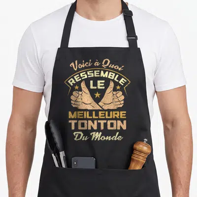 Tablier de cuisine noir avec inscription vintage et deux mains faisant des pouces levés dorés sur fond uni.