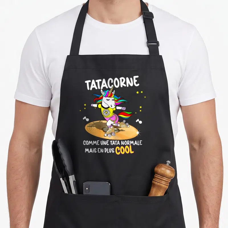 Tablier de cuisine noir avec illustration d'une licorne nommée Tatacorne sur des patins à roulettes et des notes de musique.