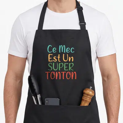 Tablier de cuisine noir avec inscription Ce Mec Est Un Super Tonton en lettres multicolores.