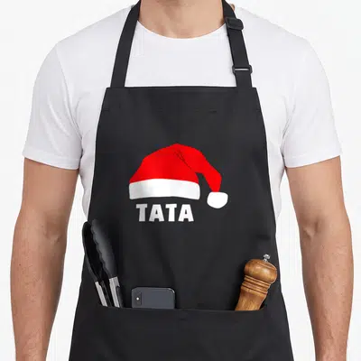 Tablier de cuisine noir avec un chapeau de Noël rouge et blanc et le mot Tata imprimé en dessous.
