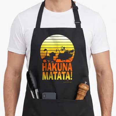 Tablier de cuisine noir avec illustration rétro du Roi Lion et texte Hakuna Matata en dégradé orange jaune.