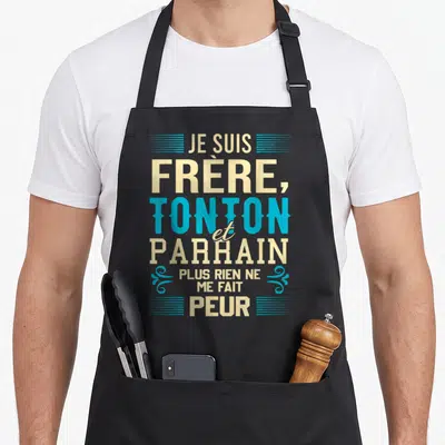 Tablier de cuisine noir avec typographie Je suis frère tonton et parrain plus rien ne me fait peur en beige et bleu cyan.