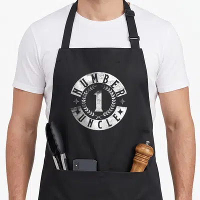 Tablier de cuisine noir avec logo circulaire blanc Number One Uncle entouré de laurier et d'étoiles.