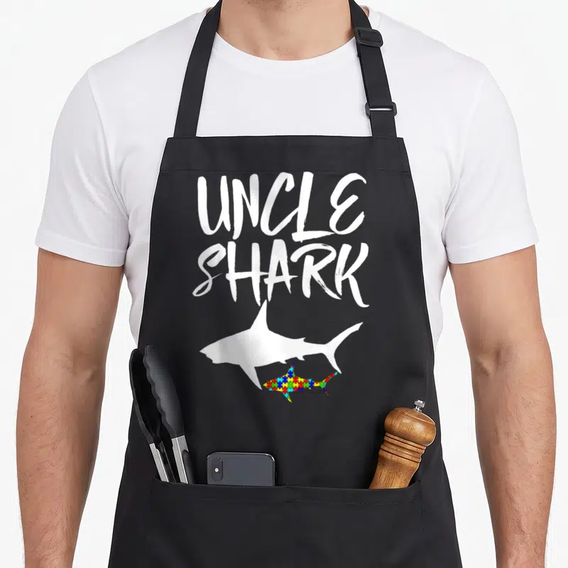 Tablier de cuisine noir avec inscription Uncle Shark et silhouettes de requins blanc et multicolore