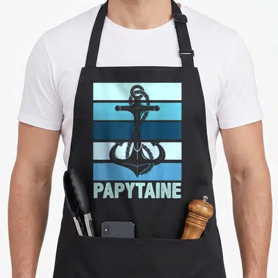 Tablier de cuisine noir avec ancre grise et texte Papytaine sur fond de bandes bleues horizontales.