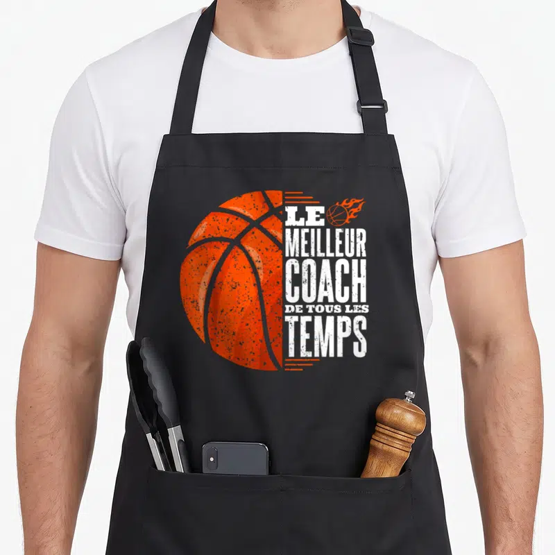 Tablier de cuisine noir avec illustration d'un ballon de basket orange et le texte Le Meilleur Coach de Tous les Temps en blanc.