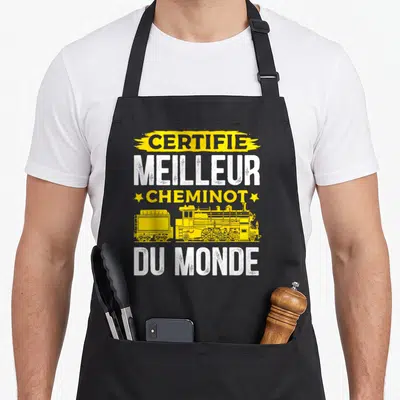 Tablier de cuisine noir avec inscription certifié meilleur cheminot du monde et illustration de locomotive jaune vintage.