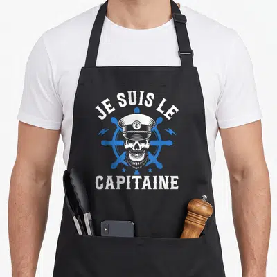 Tablier de cuisine noir avec illustration d'un crâne de capitaine et une roue de bateau bleue.