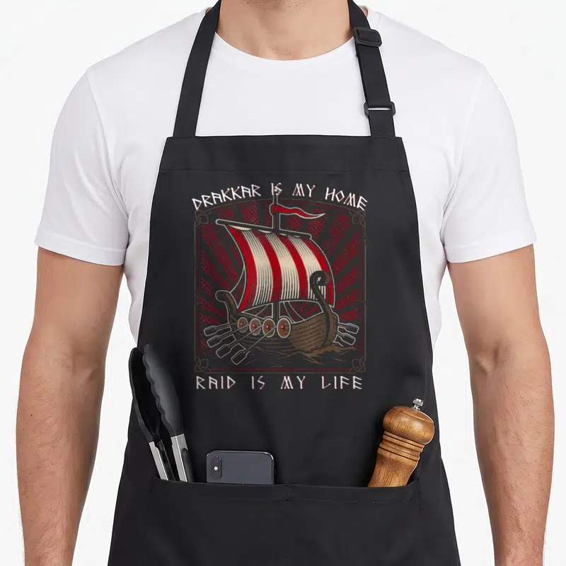 Tablier de cuisine noir avec illustration d'un drakkar aux voiles rouges et blanches et texte Drakkar Is My Home Raid Is My Life.