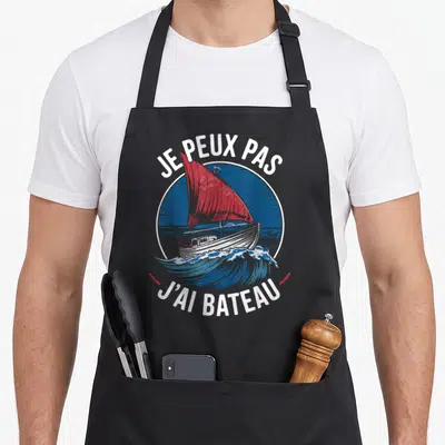 Tablier de cuisine noir avec inscription Je peux pas j'ai bateau et illustration d'un yacht à voile rouge sur mer bleue.