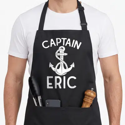 Tablier de cuisine noir avec ancre blanche, corde enroulée et texte Captain Eric imprimé en blanc.