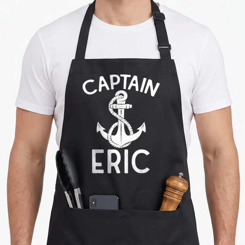 Tablier de cuisine noir avec ancre blanche, corde enroulée et texte Captain Eric imprimé en blanc.