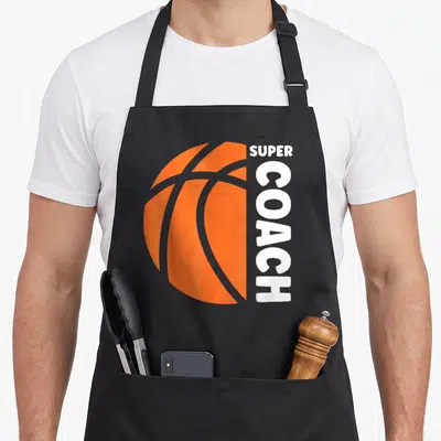 Tablier de cuisine noir avec un ballon de basket orange et le texte vertical blanc super coach