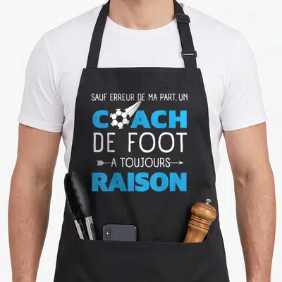 Tablier de cuisine noir avec inscription blanche et bleue sur le thème du coach de foot et d'un ballon stylisé.
