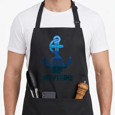 Tablier de cuisine noir avec une ancre marine bleue et l'inscription Papytaine en bas.