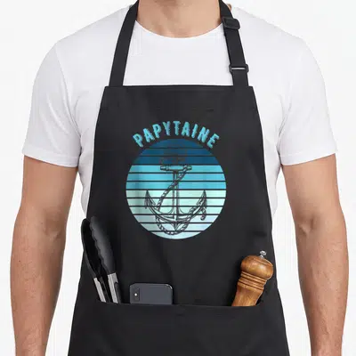 Tablier de cuisine noir avec une ancre et l'inscription Papytaine en bleu sur fond rayé.