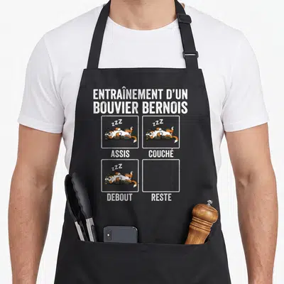 Tablier de cuisine noir avec illustration d'un Bouvier Bernois dormant dans des cases de commandes.