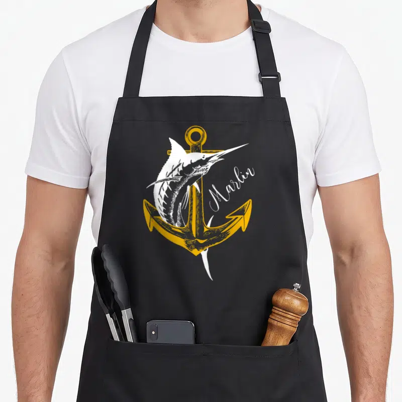 Tablier de cuisine noir avec un marlin blanc, une ancre jaune et le texte Marlin en calligraphie.