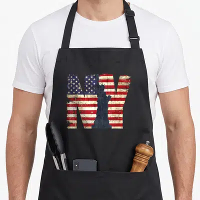 Tablier de cuisine noir avec les lettres NY en drapeau américain et statue de la Liberté en silhouette.
