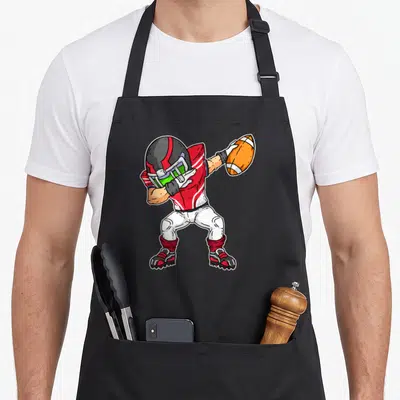 Tablier de cuisine noir avec joueur de football américain en tenue rouge et blanche tenant un ballon orange.