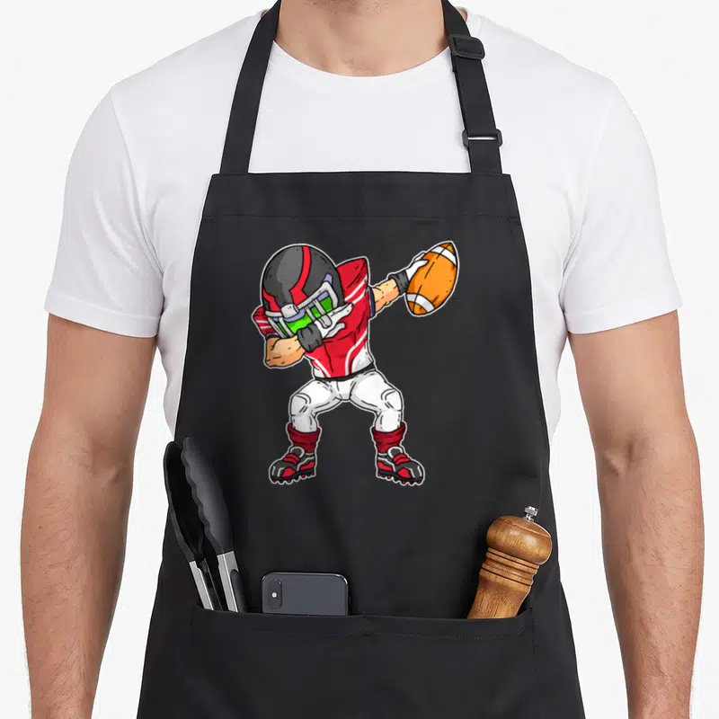 Tablier de cuisine noir avec joueur de football américain en tenue rouge et blanche tenant un ballon orange.