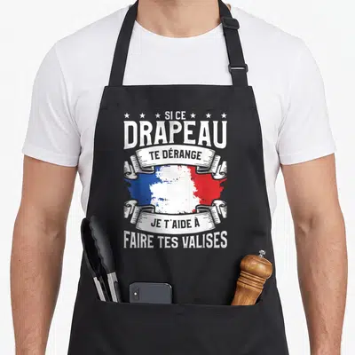 Tablier de cuisine noir avec illustration du drapeau français et texte blanc Si ce drapeau te dérange je t'aide à faire tes valises.