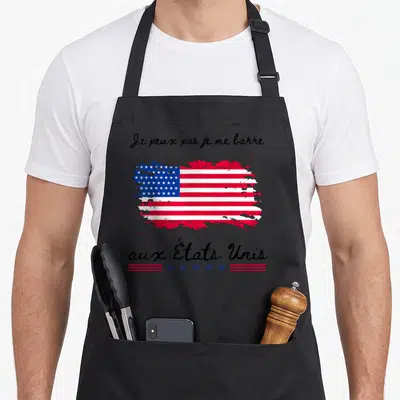 Tablier de cuisine noir avec drapeau américain brossé et texte Je peux pas je me barre aux États Unis imprimé en noir.