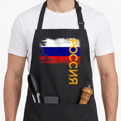Tablier de cuisine noir avec drapeau russe stylisé et texte vertical Rossia en orange sur fond gris.