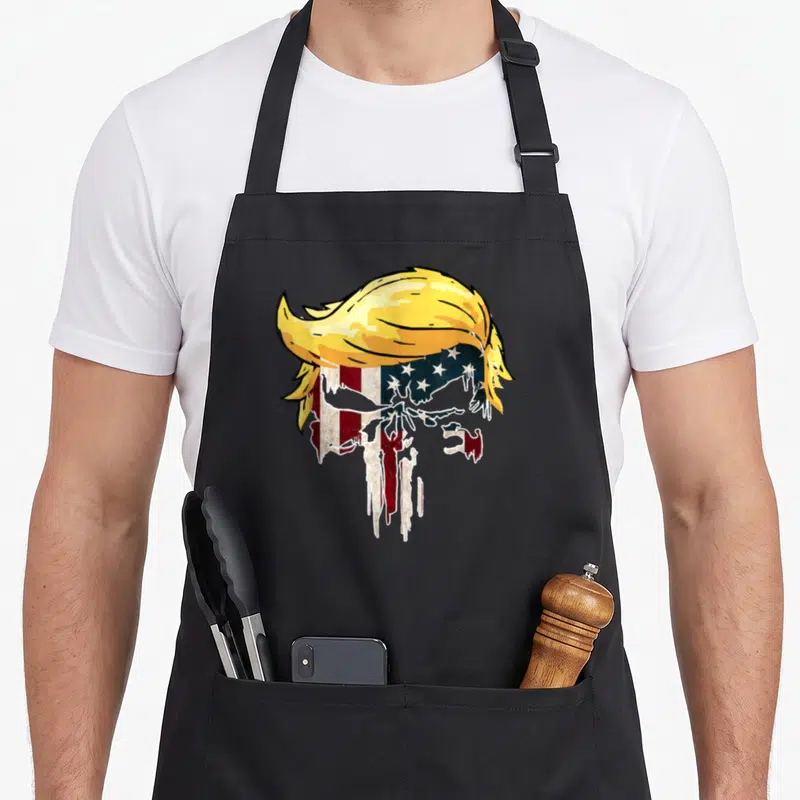 Tablier de cuisine noir avec un crâne portant une coiffure blonde et des motifs du drapeau américain dégradés.
