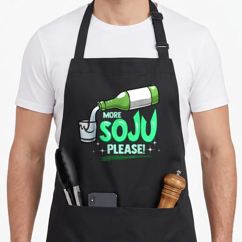 Tablier de cuisine noir avec illustration d'une bouteille verte versant du soju et le texte More Soju Please en lettres vertes stylisées.