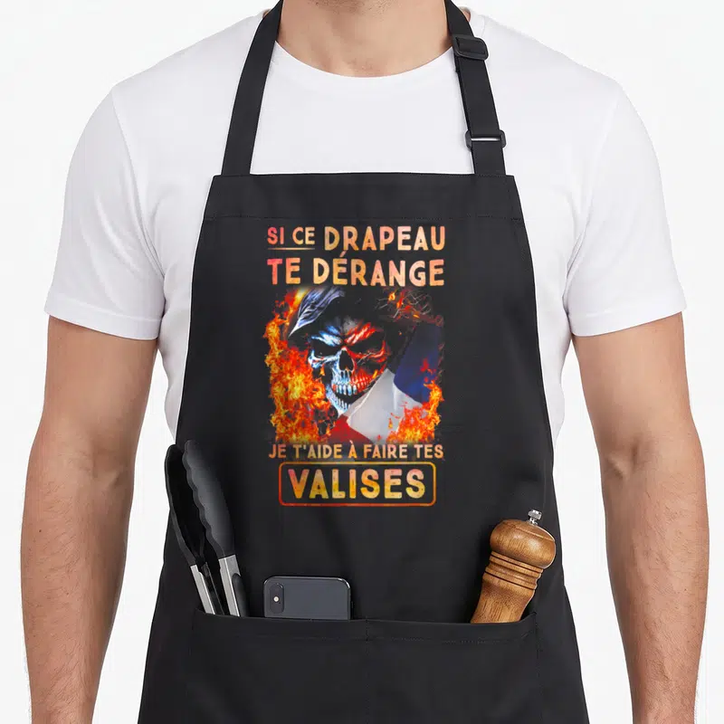 Tablier de cuisine noir avec un crâne enflammé et un drapeau aux couleurs vives au centre du motif.