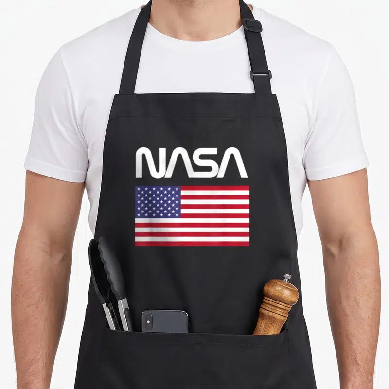 Tablier de cuisine noir avec logo NASA Worm et drapeau des États-Unis imprimé sur le devant.