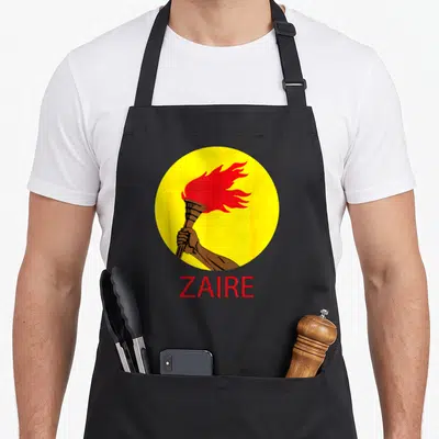 Tablier de cuisine noir avec un cercle jaune contenant une main tenant une torche à flamme rouge et le mot ZAIRE en dessous.