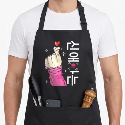 Tablier de cuisine noir avec main formant un doigt cœur, texte YOHAT et drapeau sud-coréen stylisé.