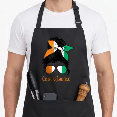 Tablier de cuisine noir avec une femme ivoirienne portant un foulard et des lunettes aux couleurs du drapeau national.